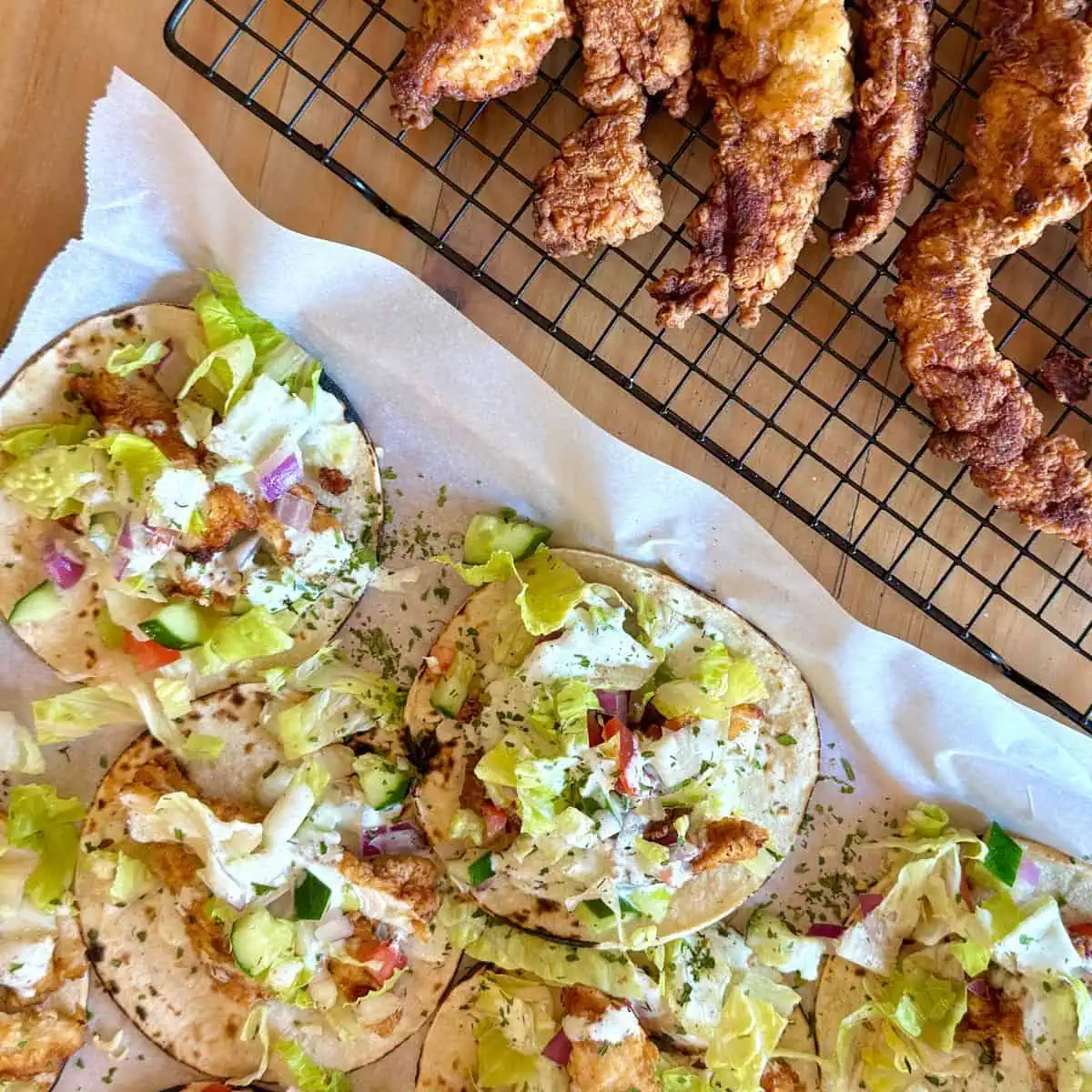 Display of ingredients for buttermilk chicken tender tacos including chicken, buttermilk, flour, eggs, breadcrumbs, and fresh vegetables.