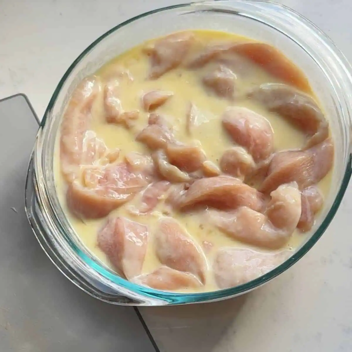 Chicken tenders marinating in seasoned buttermilk.