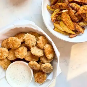 Homemade chicken nuggets with a bowl of homemade ranch sauce and potato wedges.