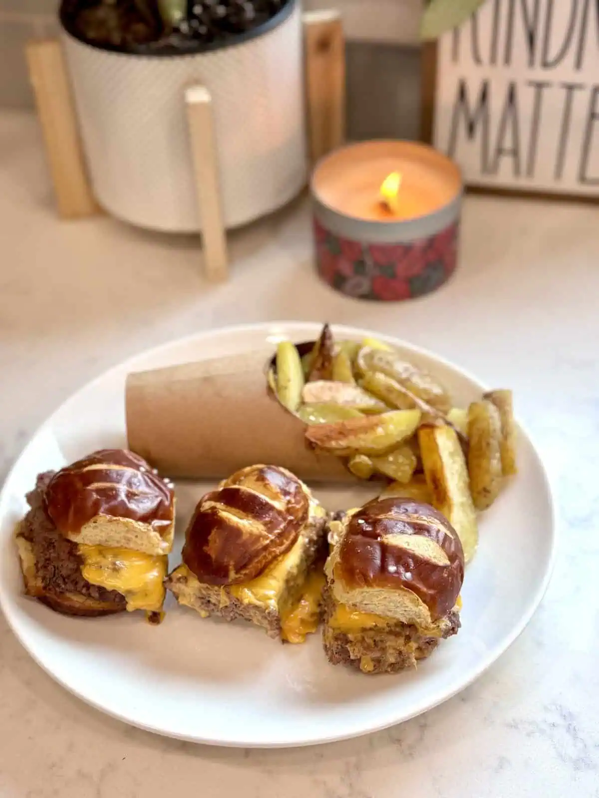 A different angle of the pretzel bun cheeseburger sliders served with homemade fries.