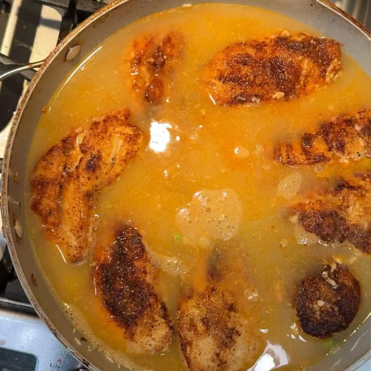 Chicken broth added to the rice and vegetables in the pan. 