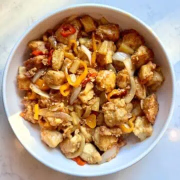 Straight-on view of pineapple chicken with sweet peppers served on a plate.