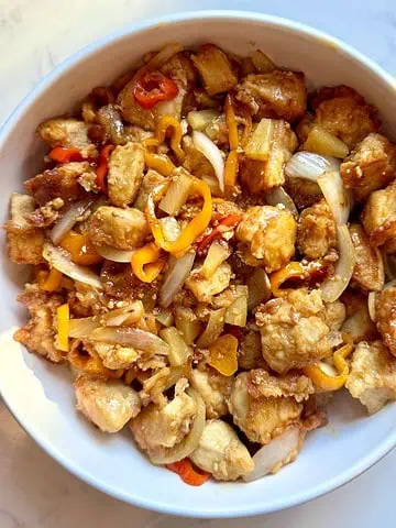 Straight-on view of pineapple chicken with sweet peppers served on a plate.