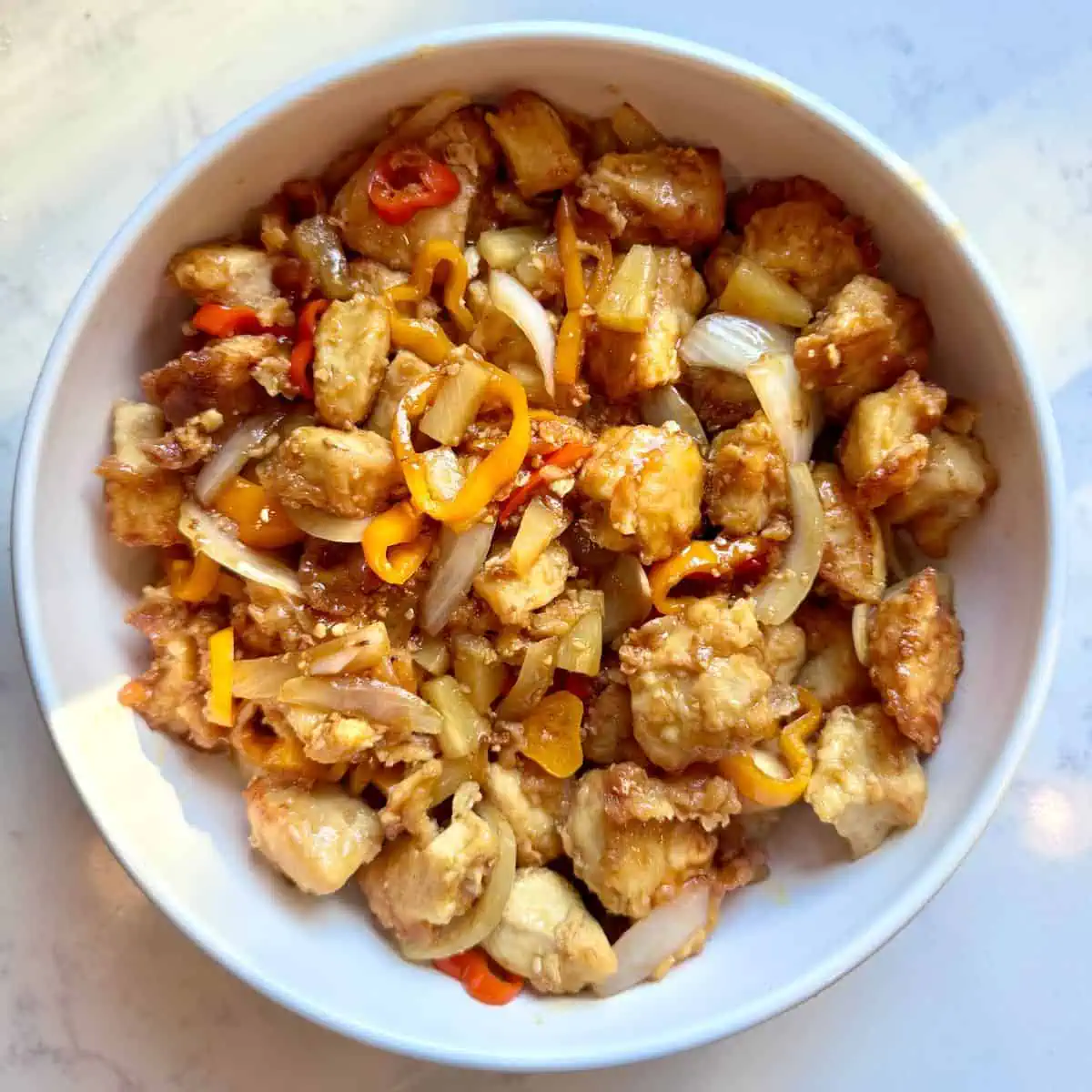 Straight-on view of pineapple chicken with sweet peppers served on a plate.