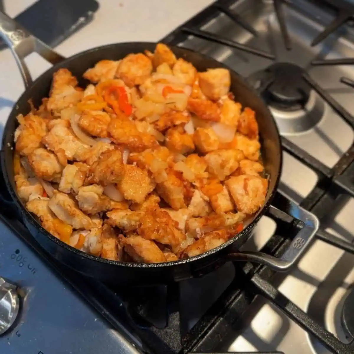 The fully assembled ingredients for pineapple chicken with sweet peppers cooking in a pan.