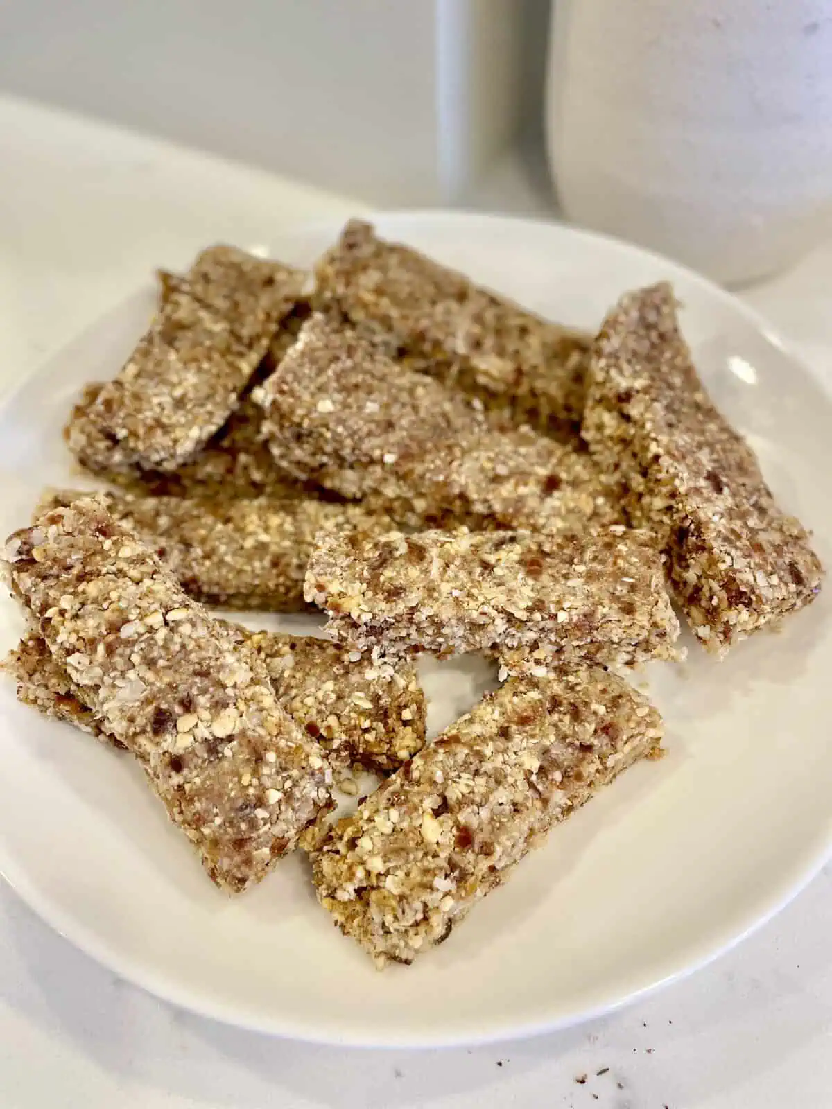 A stack of homemade no-bake granola bars on a wooden cutting board, with a drizzle of melted chocolate.