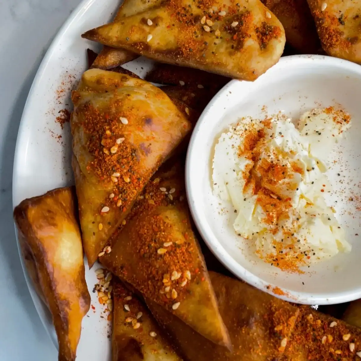 A plate of homemade snackers arranged around a small dish of seasoned butter.