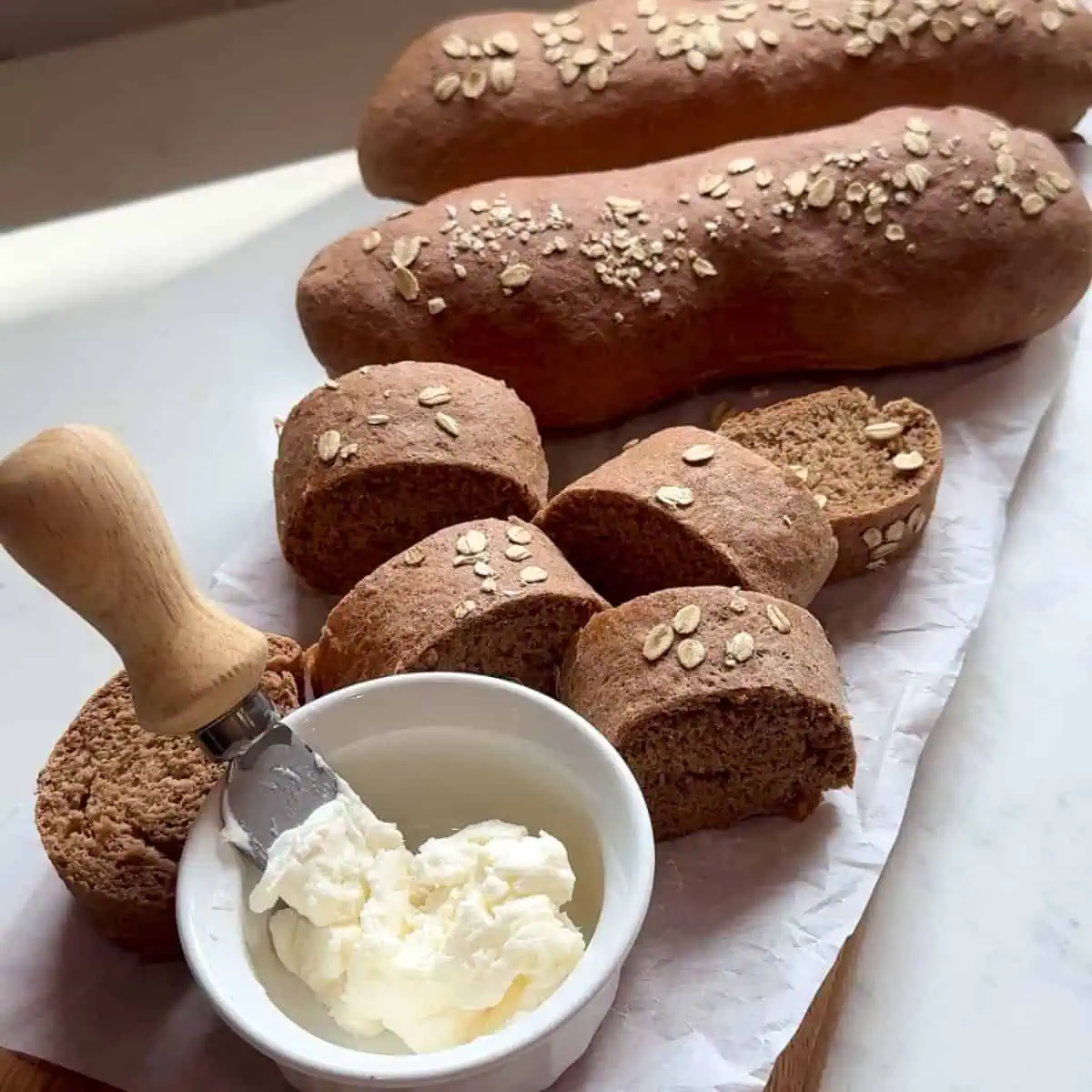 Sliced honey wheat bread loaf with butter ready to spread