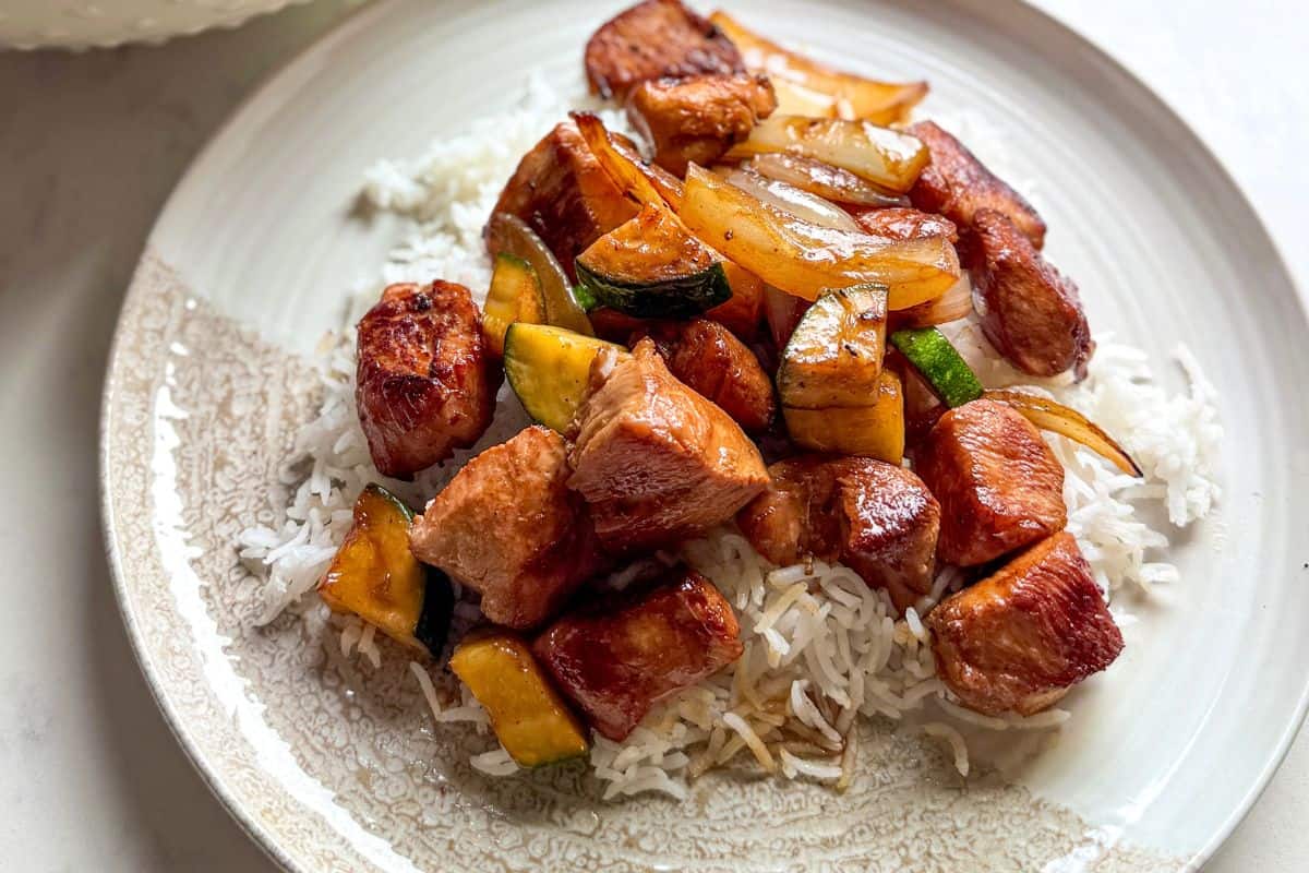Cast iron hibachi chicken and vegetables plated over rice, styled for a blog cover.