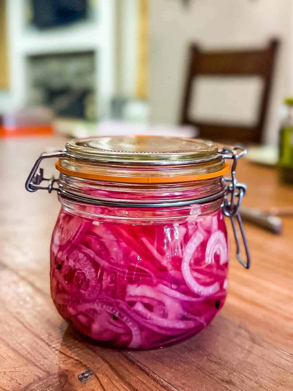 Bright pink pickled red onions after soaking overnight in a mason jar