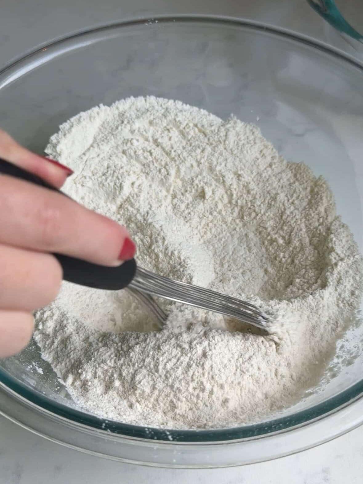 Whisking flour, sugar, baking powder, baking soda, and salt in a mixing bowl.