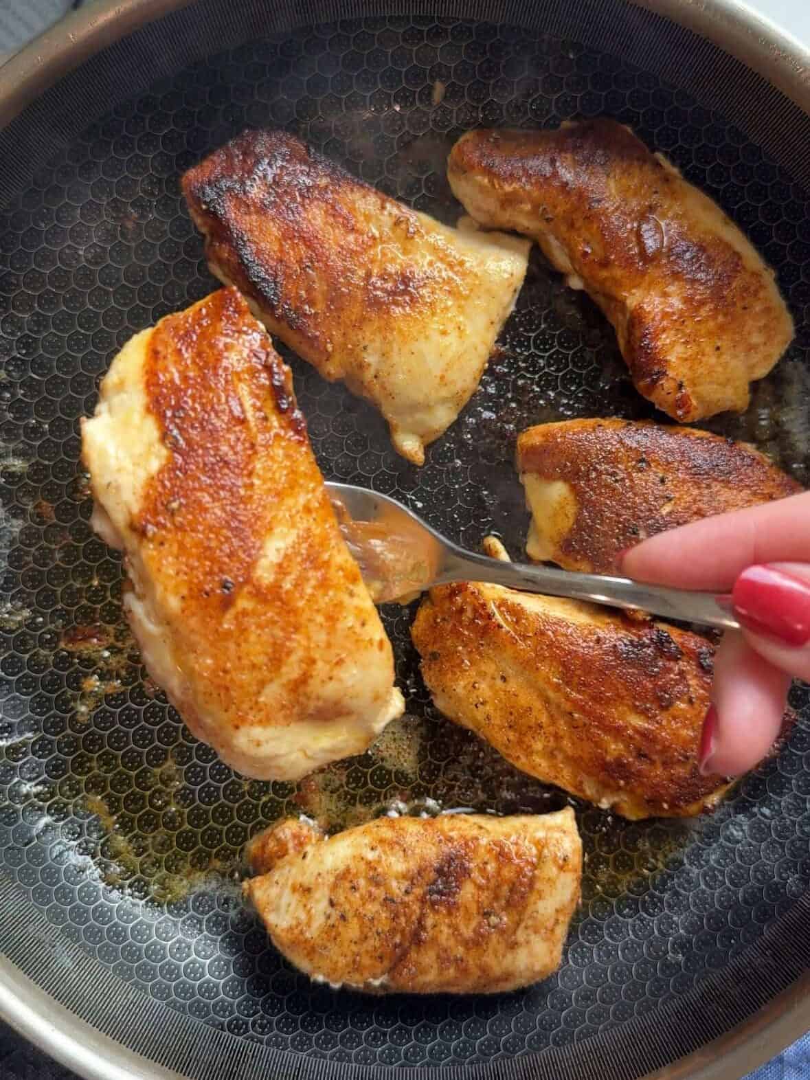 Golden brown seared chicken being removed from skillet before cooking rice and green beans