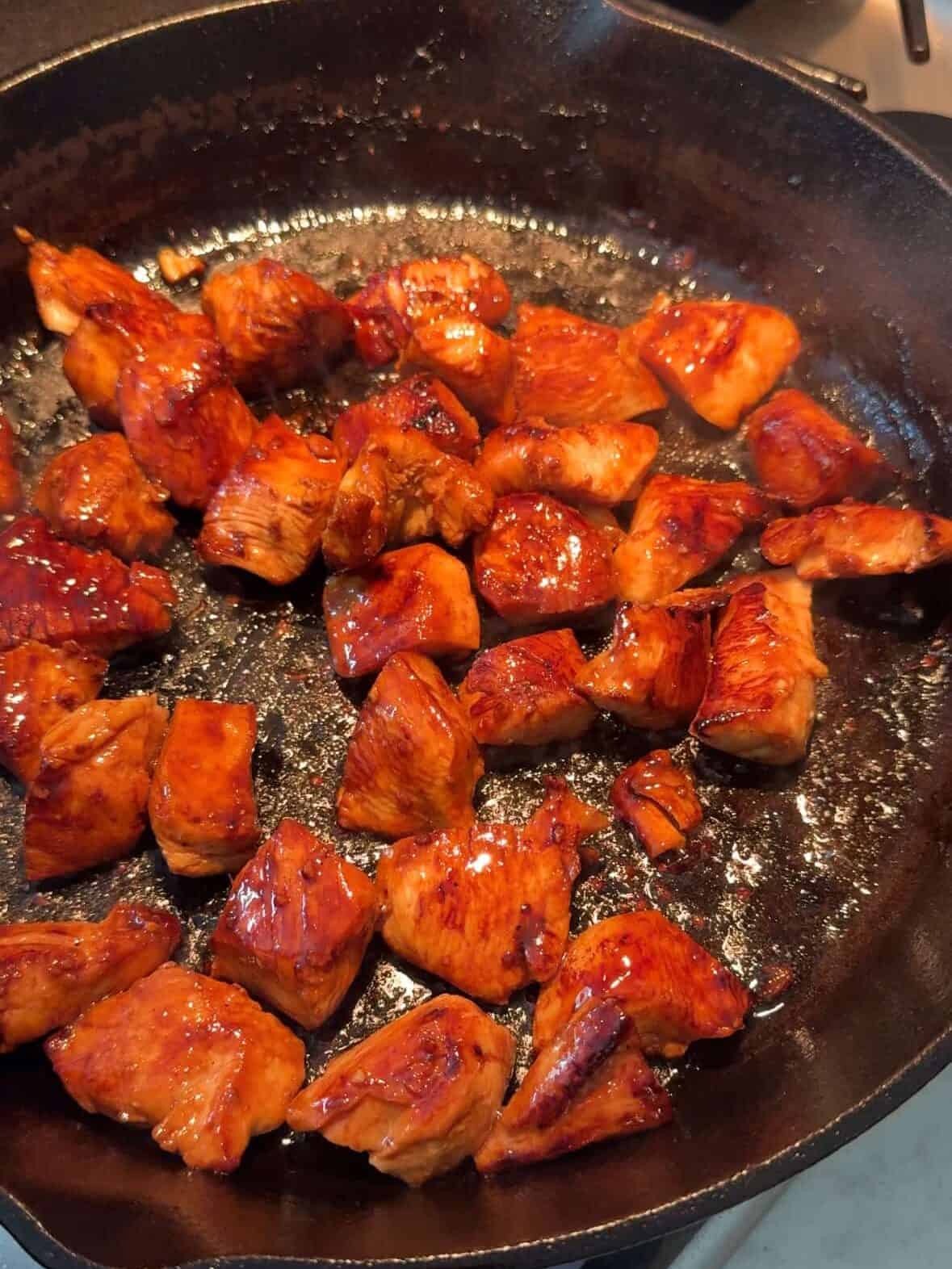 Chicken browning in a hot cast iron skillet with golden seared edges.