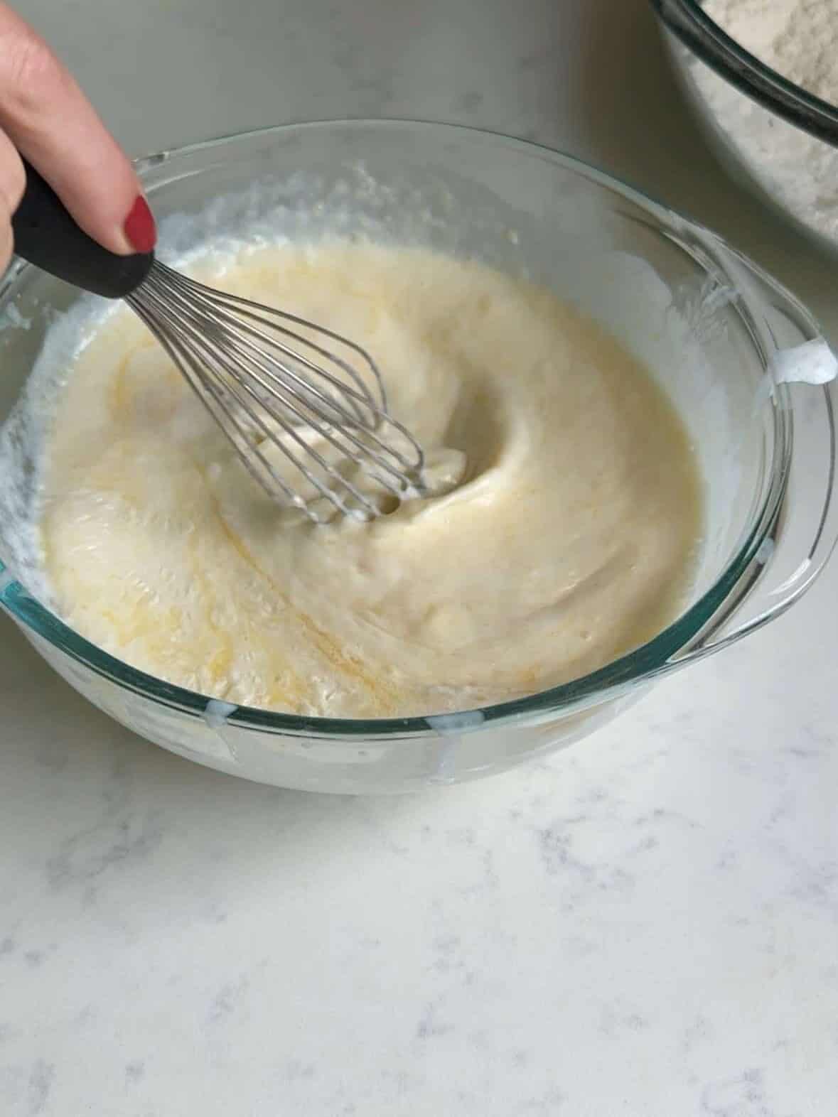 Eggs, buttermilk, melted butter, and vanilla being mixed in a bowl.