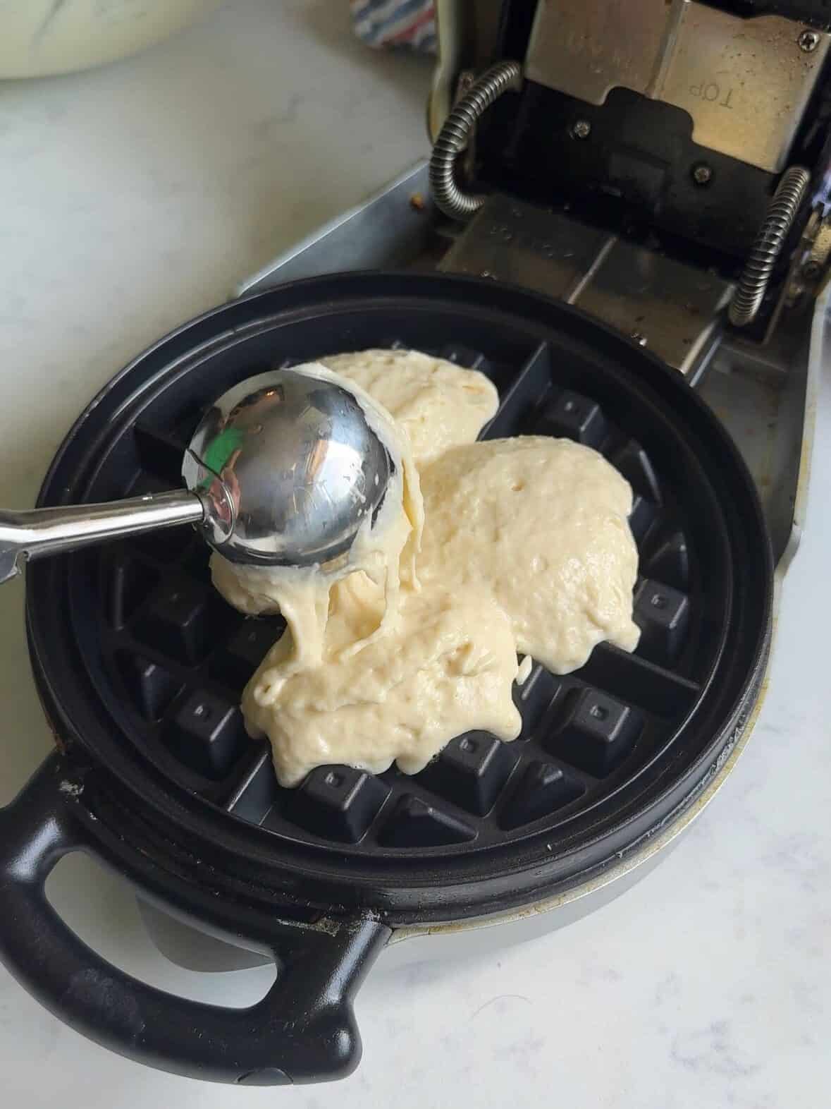 Waffle batter being poured into a preheated waffle iron.