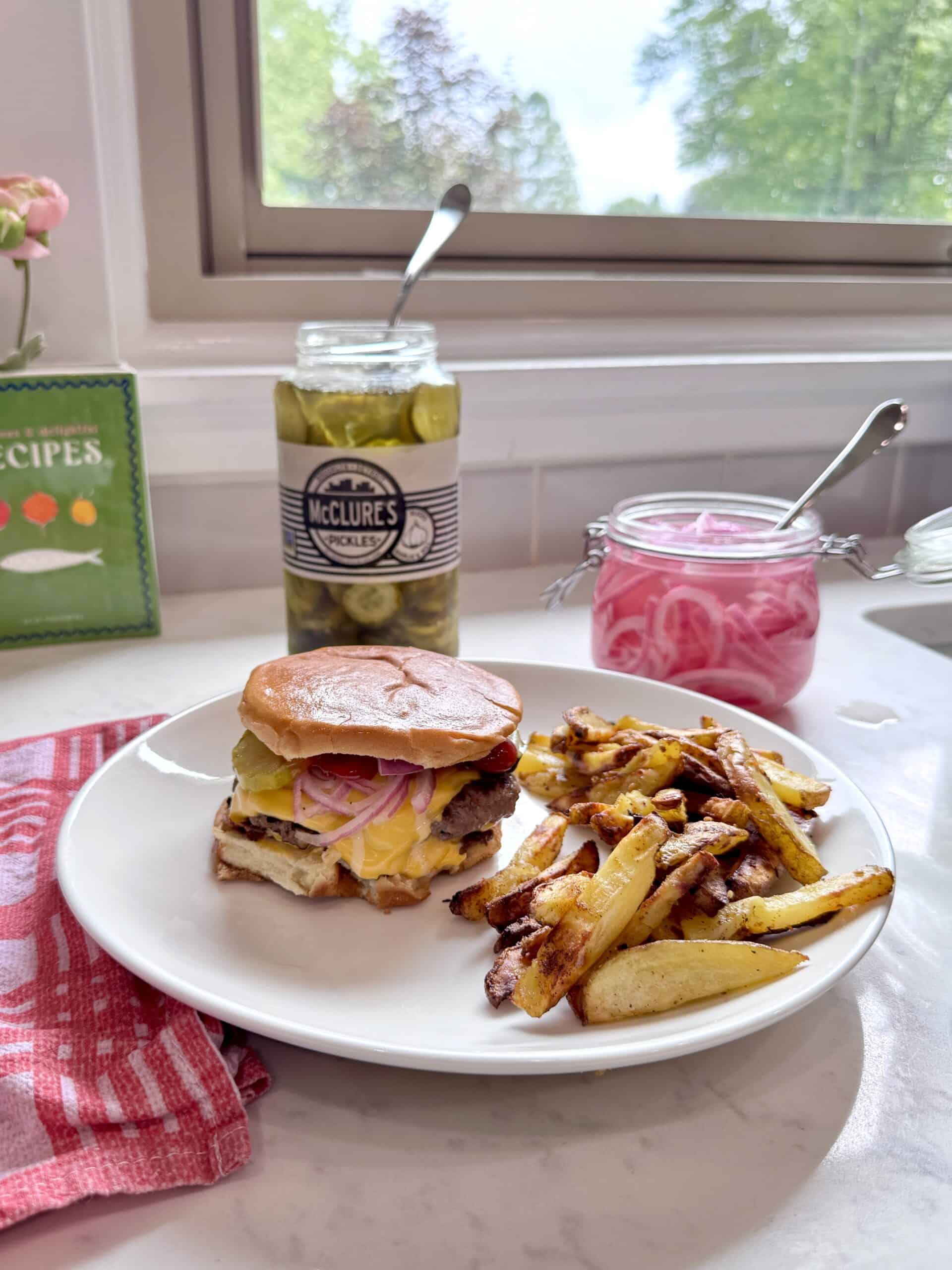 Plate of smash burgers and fries with pickled onions and pickles