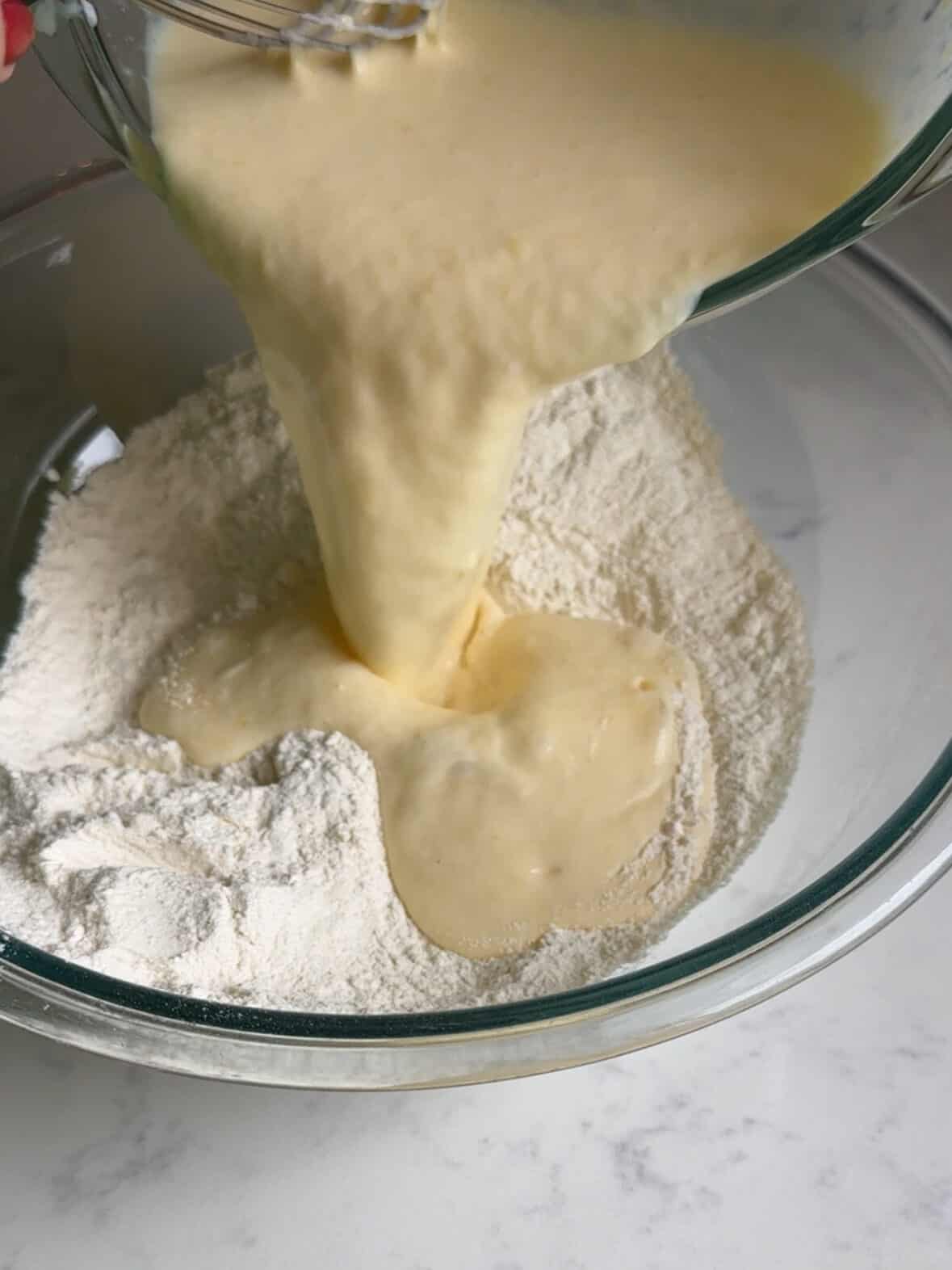 Wet ingredients being poured into dry ingredients and gently mixed.