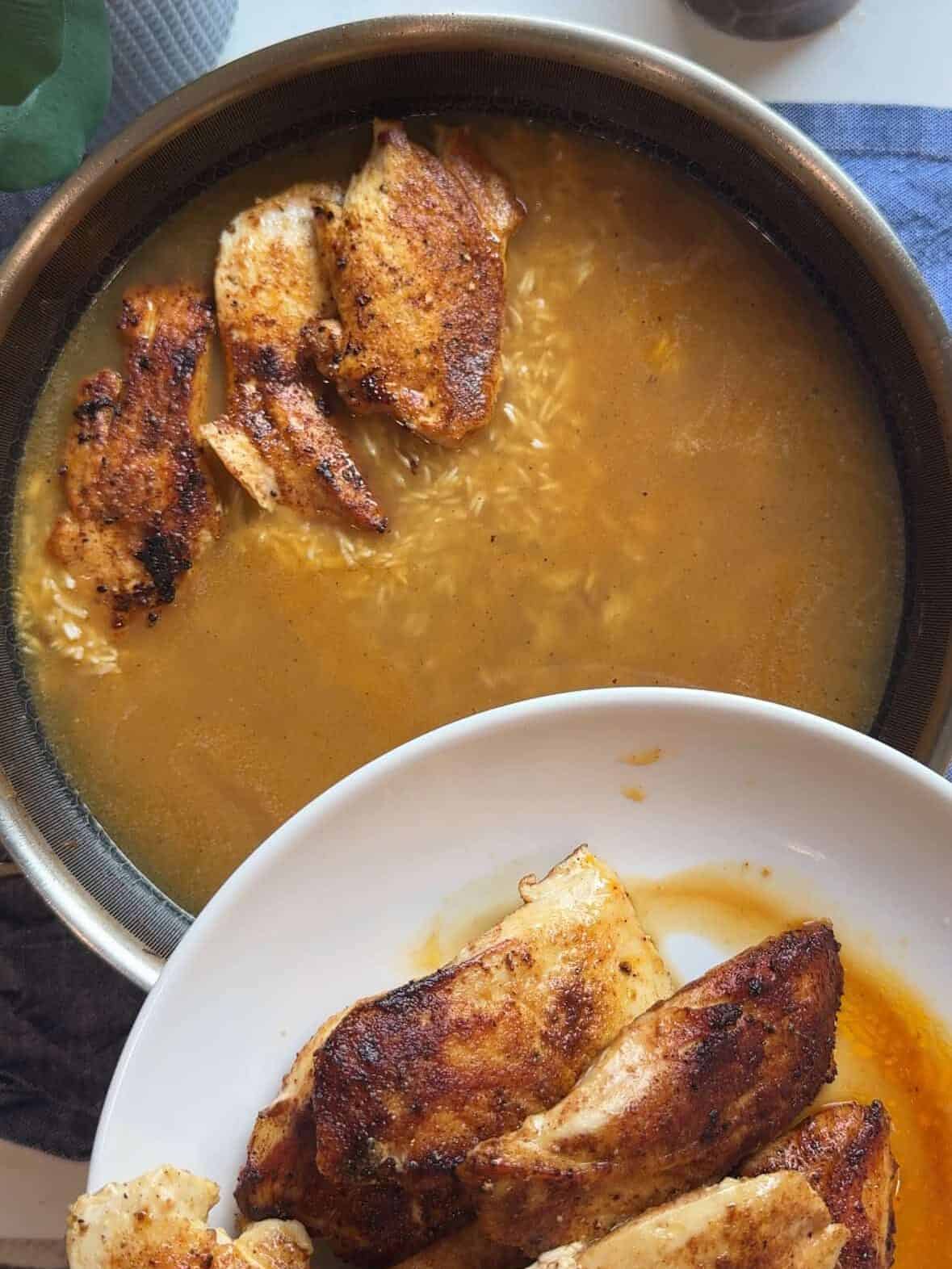 Seared chicken placed on top of rice and green beans in skillet before final cooking