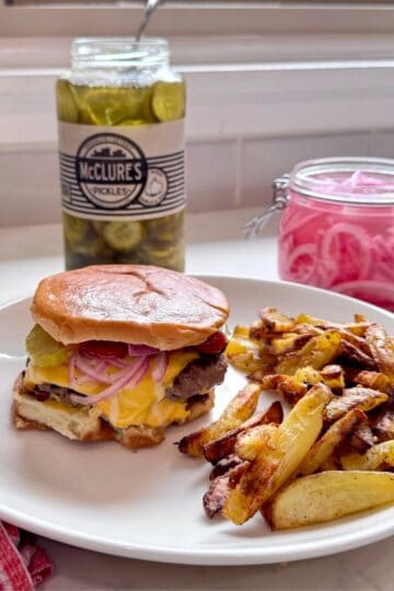 Smash burger plated with crispy homemade fries, ready to serve.
