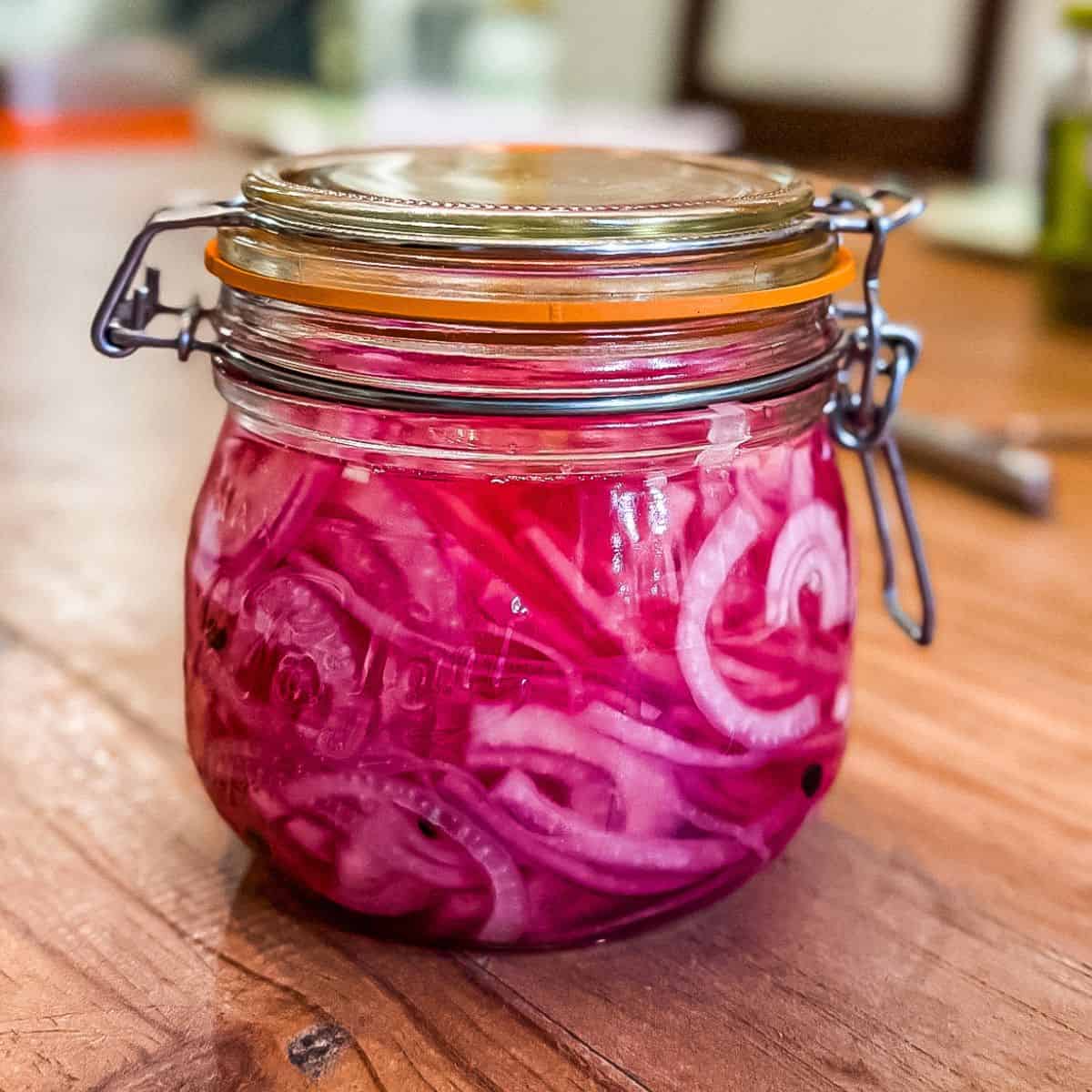 Bright pink pickled red onions after soaking in a mason jar