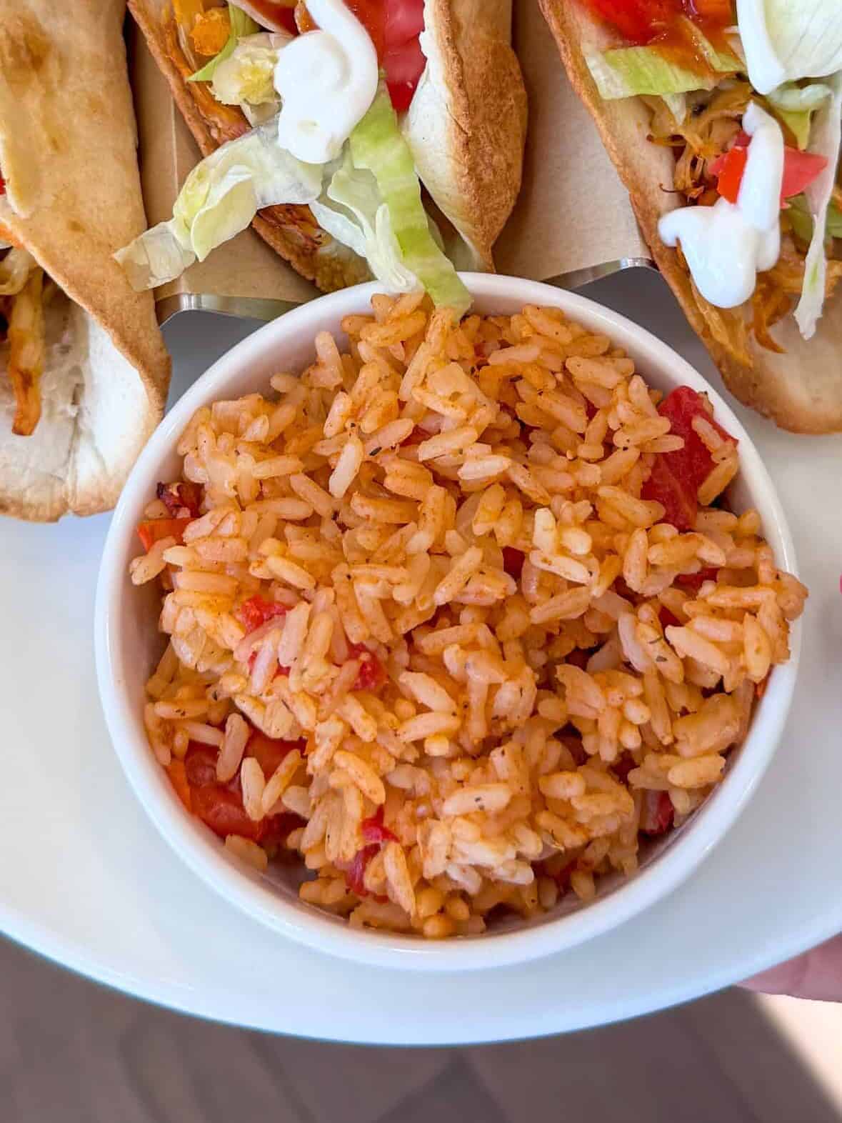 Easy Spanish rice with tacos and vegetables on dinner table.