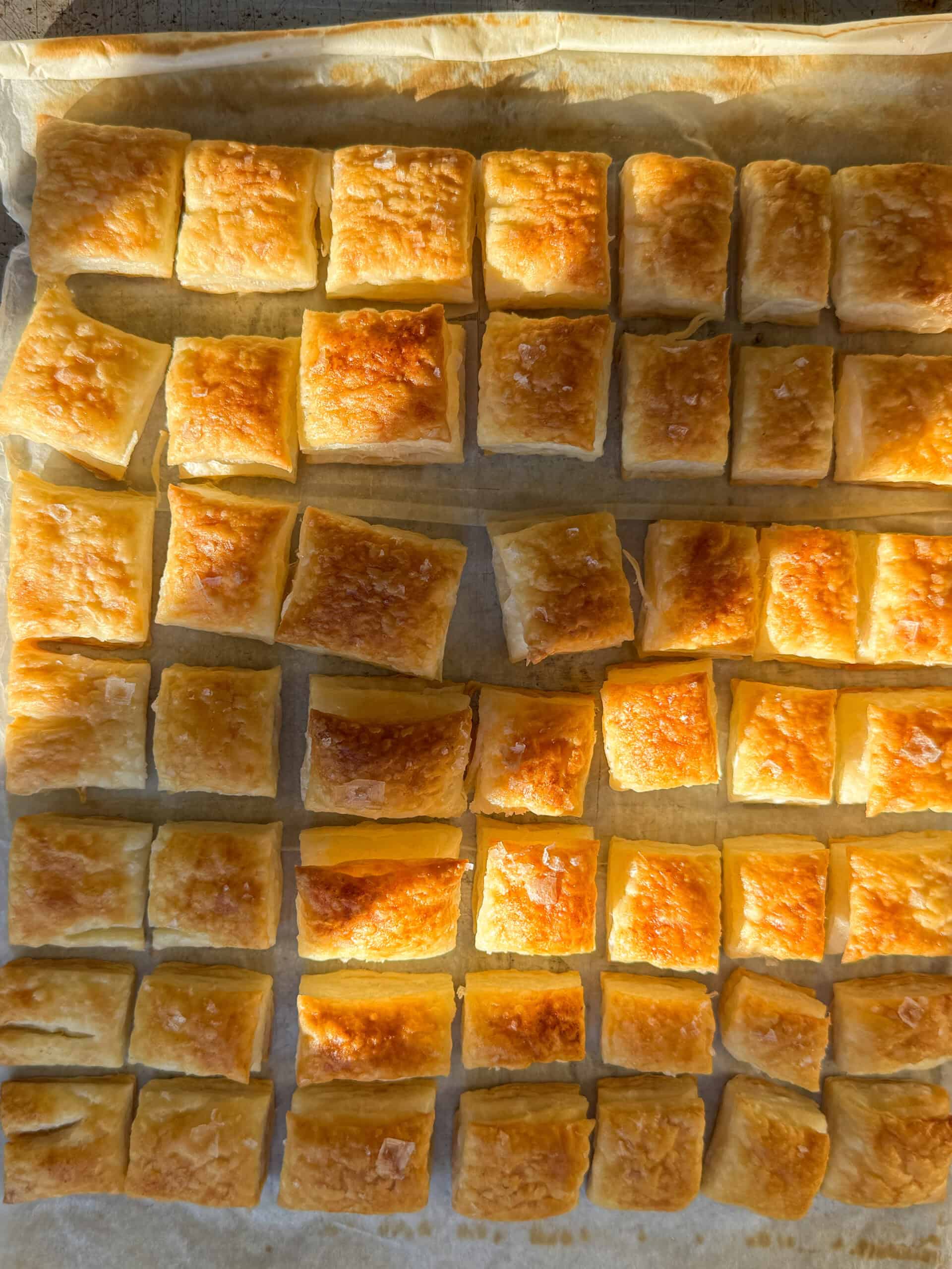 Overhead view of baked puff pastry squares topped with flaky sea salt