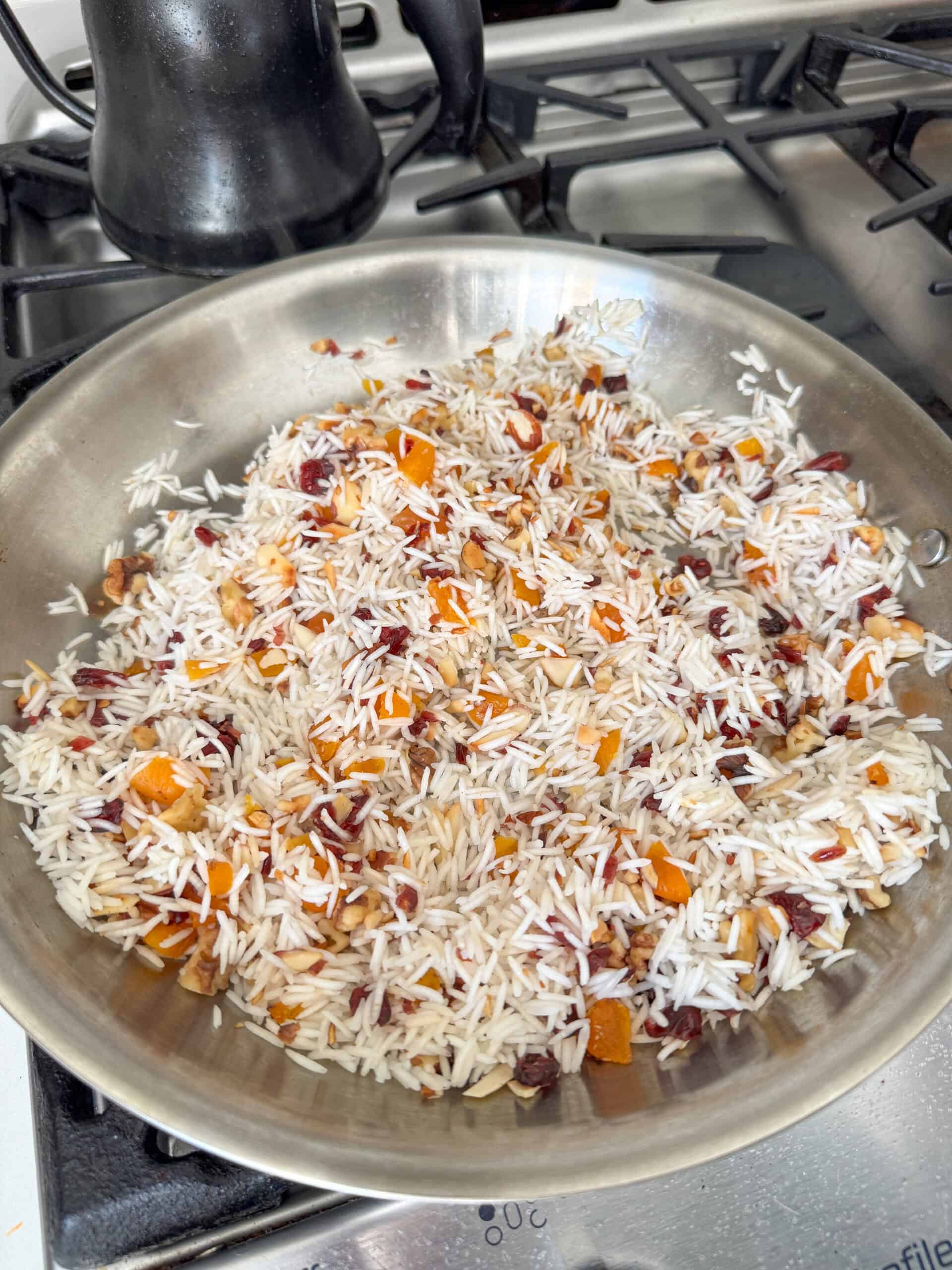 Basmati rice mixed with dried apricots, Craisins, walnuts, and almonds in a skillet