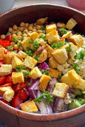 Greek cucumber tomato salad with feta, olives, and homemade croutons, fully mixed