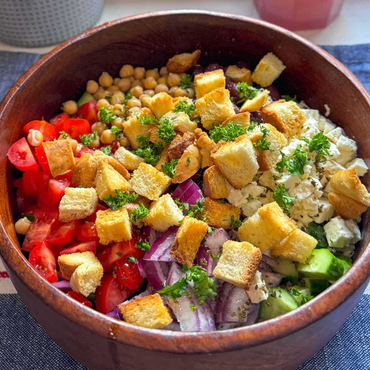 Greek cucumber tomato salad with feta, olives, and homemade croutons, fully mixed