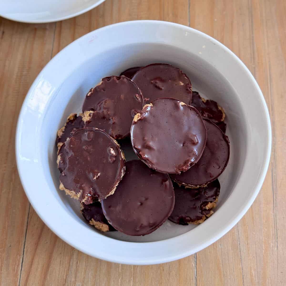Bowl filled with protein peanut butter rice cake cups topped with dark chocolate and sea salt flakes.