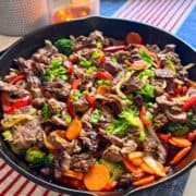Cast iron skillet filled with steak and vegetable stir-fry shot from above at an angle