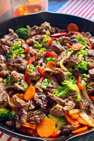 Cast iron skillet filled with steak and vegetable stir-fry shot from above at an angle