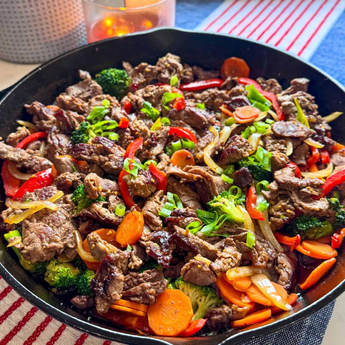 Cast iron skillet filled with steak and vegetable stir-fry shot from above at an angle