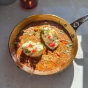One-pan creamy pesto burrata chicken topped with tomatoes, basil, and parmesan in a skillet.