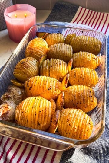 Close-up image of baked Hasselback potatoes in a glass dish, highlighting the crispy edges and layers.