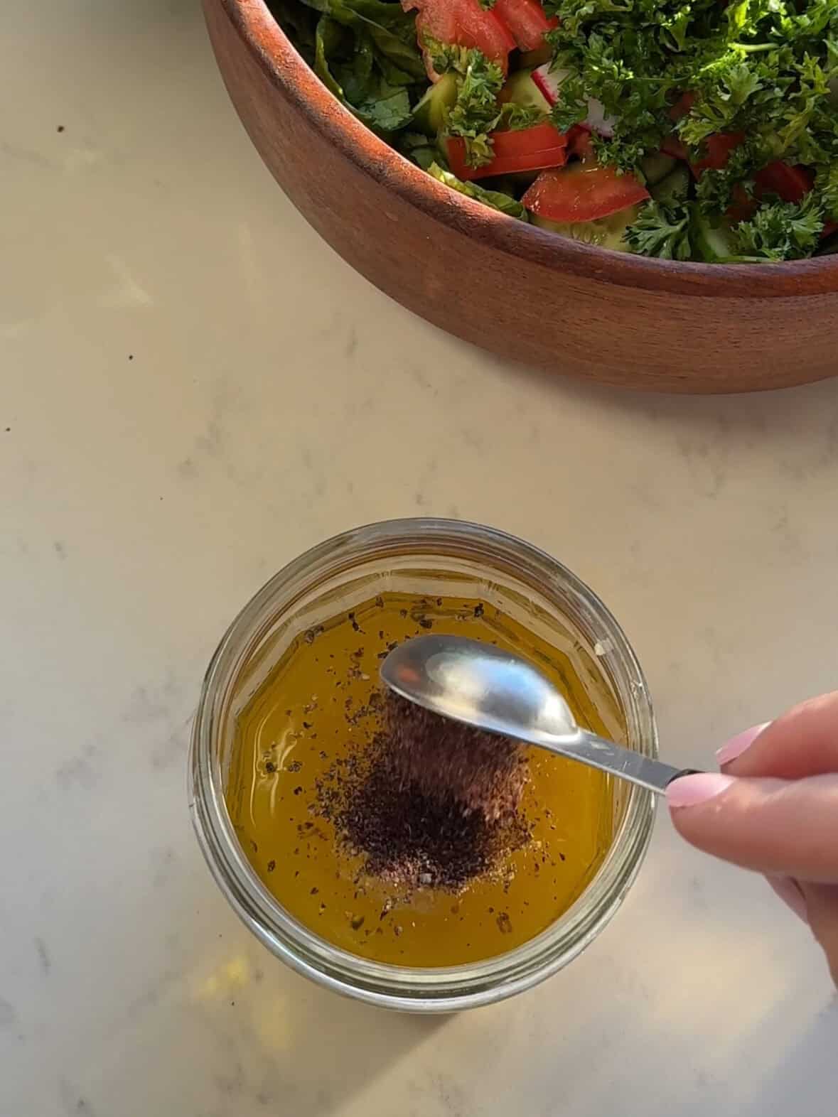 Mixing homemade fattoush salad dressing ingredients in a mason jar for a bright Middle Eastern flavor.