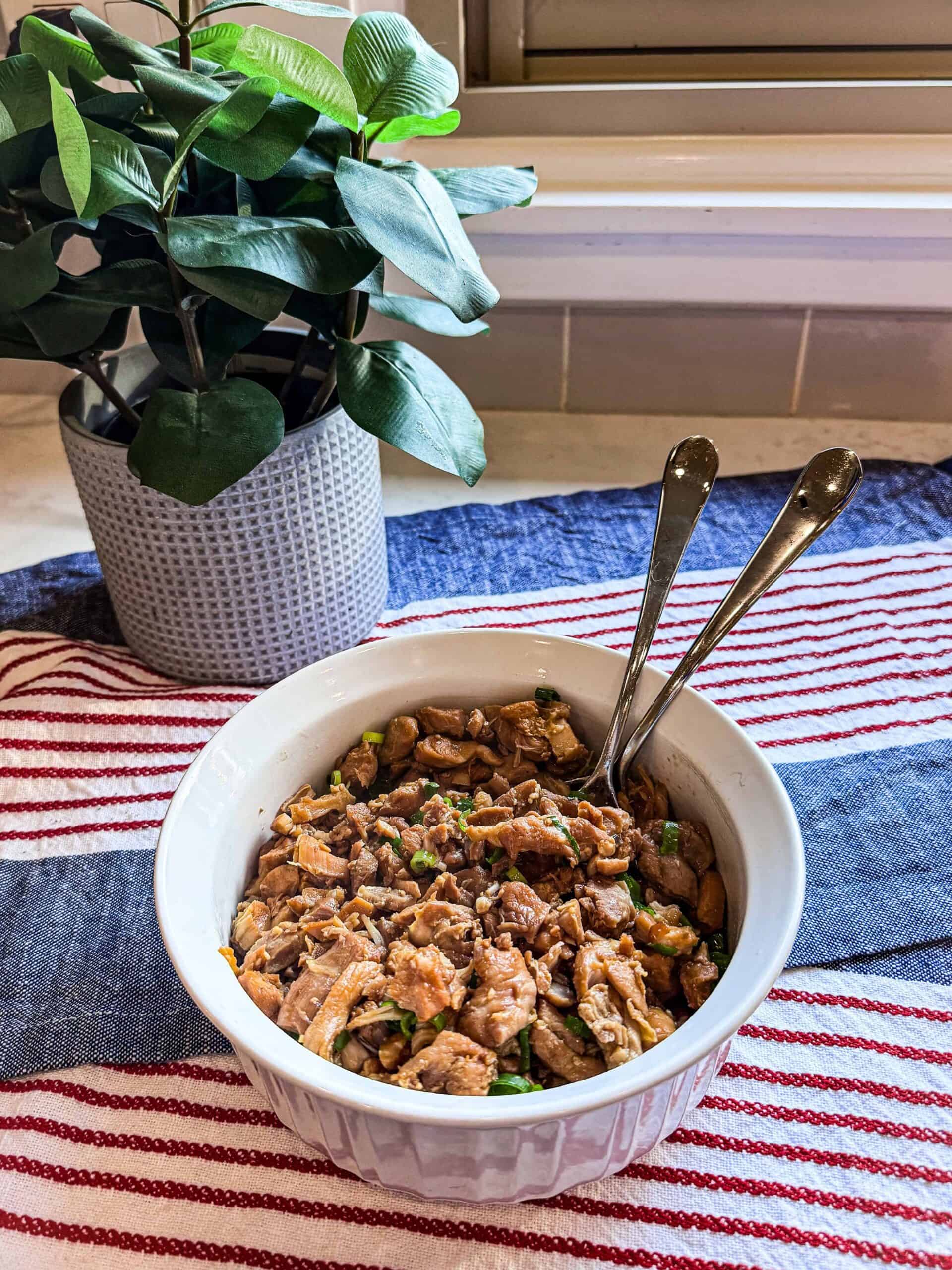 Overhead view of Easy Honey Soy Chicken thighs served in a white bowl on a neutral tablecloth.