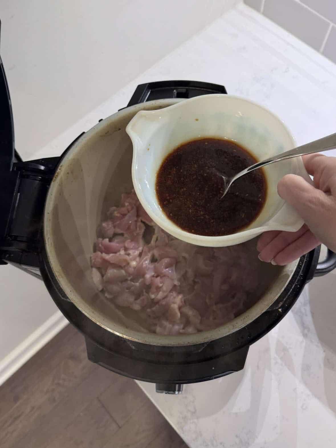 Raw chicken coated in honey soy sauce inside an Instant Pot before pressure cooking.