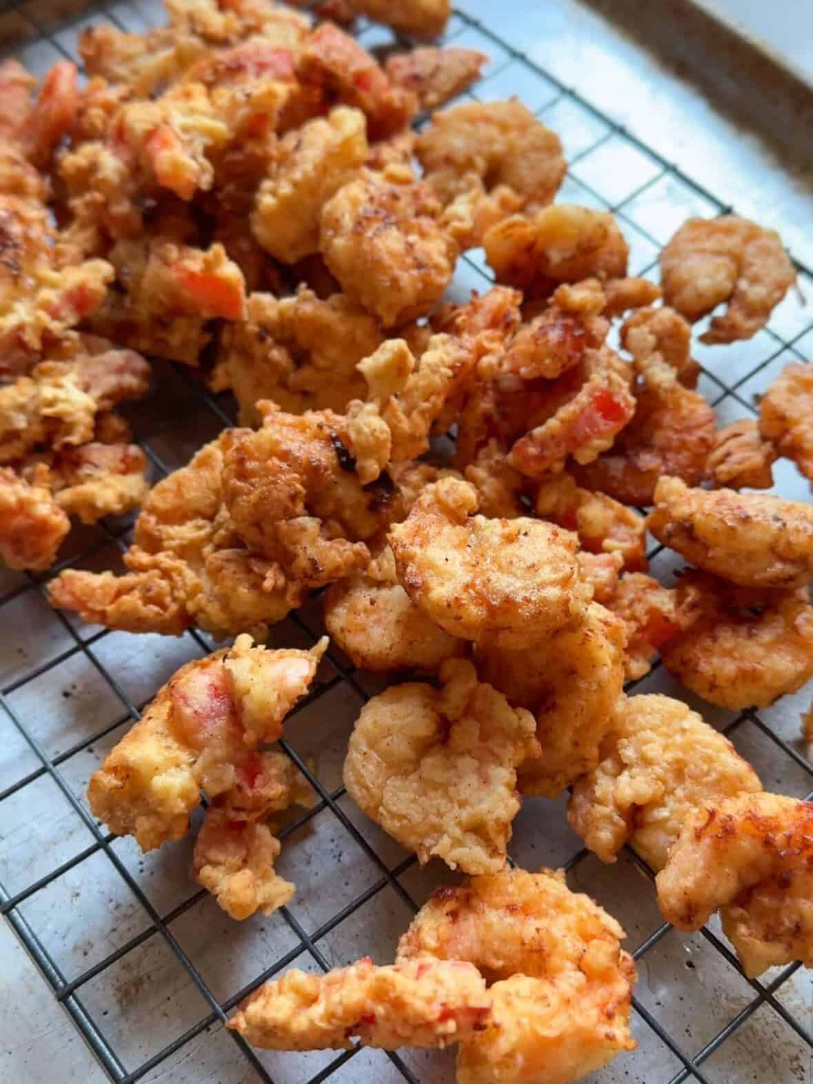 Crispy shrimp scampi fritta draining on a cooling rack after frying, sprinkled with fresh parsley.