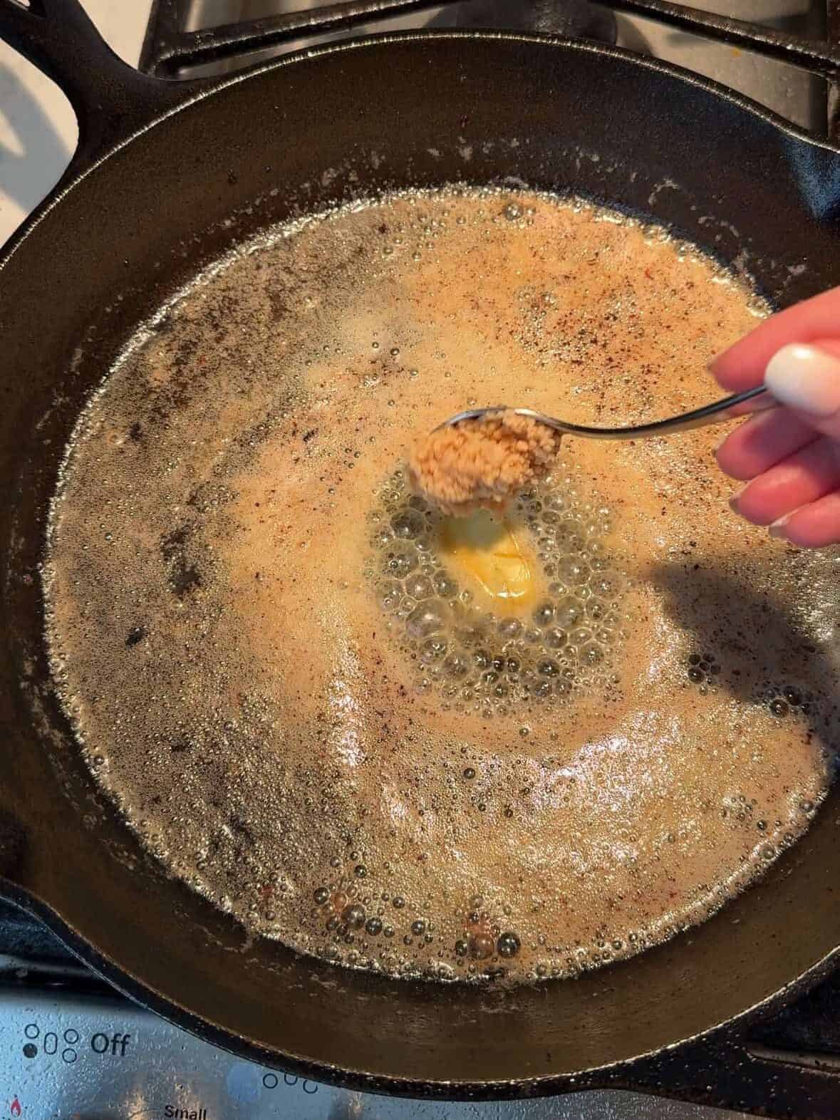 Butter and minced garlic melting in cast iron pan after searing steak.