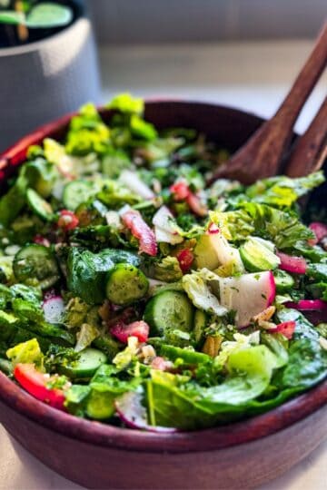 Close-up 45-degree view of Armenian-inspired fattoush salad with crunchy pita chips in a wooden salad bowl.