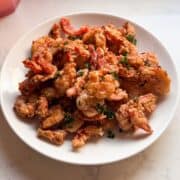 Angled shot of Shrimp Scampi Fritta on a plate with parsley and flaky sea salt, showing the crisp golden coating.