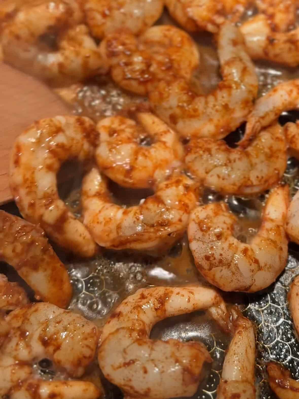 Shrimp cooking in a skillet, turning pink as it sautés for the shrimp with spinach and pasta recipe.