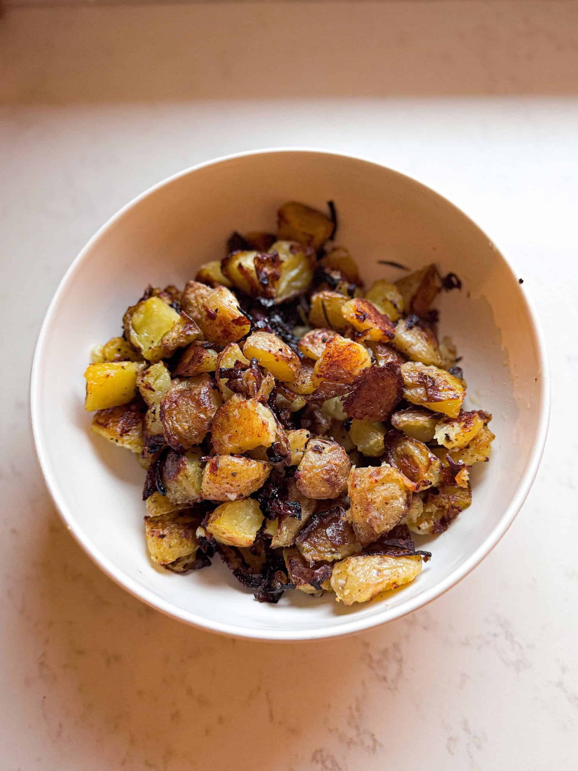 Crispy roasted potatoes served in a white bowl.