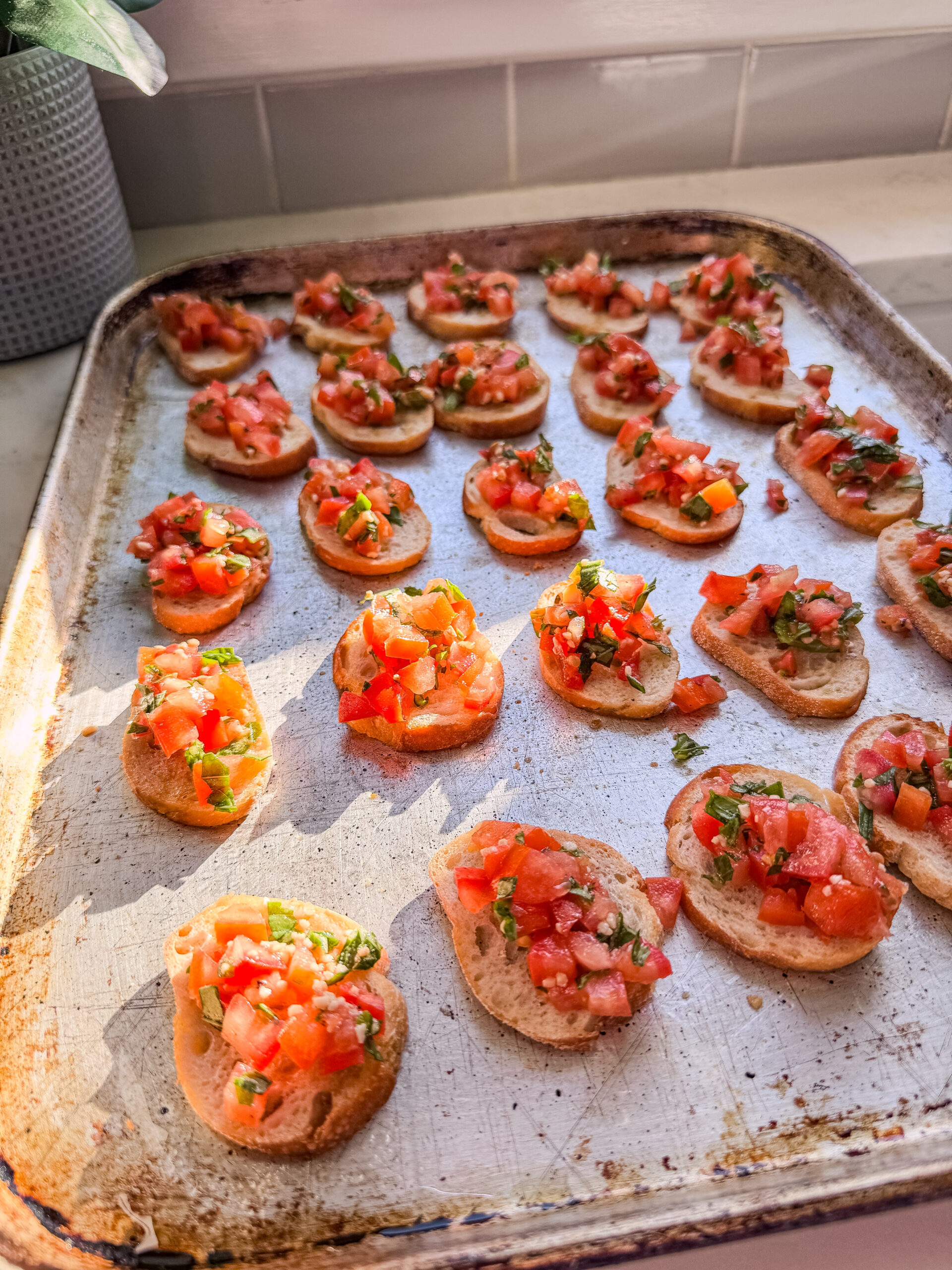 Close-up of vegan bruschetta topped crostini on baking sheet.
