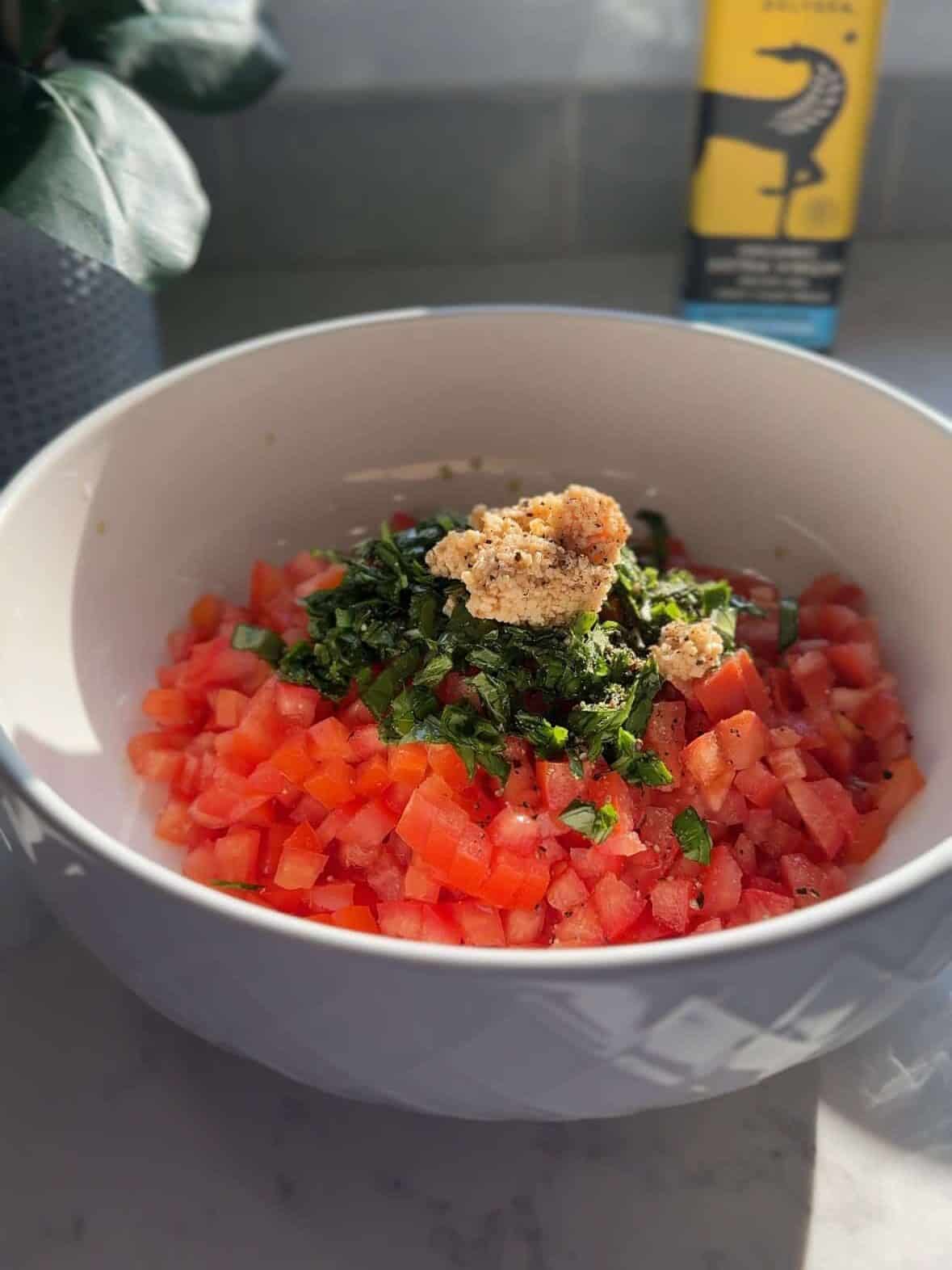 Fresh tomatoes, basil, garlic, salt, and pepper in a bowl before making bruschetta.