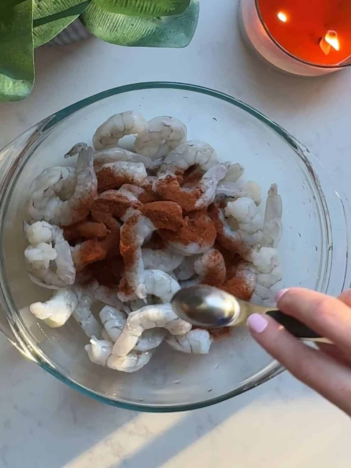 Raw shrimp seasoned with paprika, salt, and pepper in a bowl for shrimp with spinach and pasta.