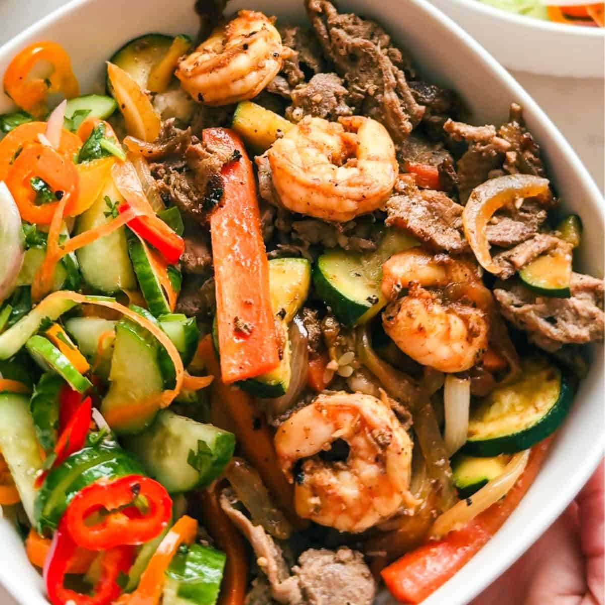 Close-up detail of steak and shrimp hibachi bowls showing shrimp and sliced steak over rice in a hibachi-style stir-fry recipe.