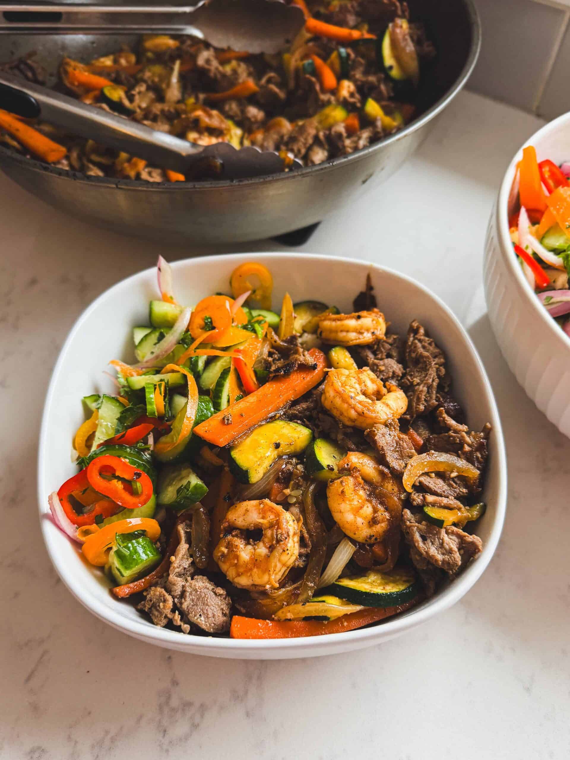 Close-up of steak and shrimp hibachi bowls with rice and vegetables, showing hibachi-style flavors cooked using a stir-fry method.