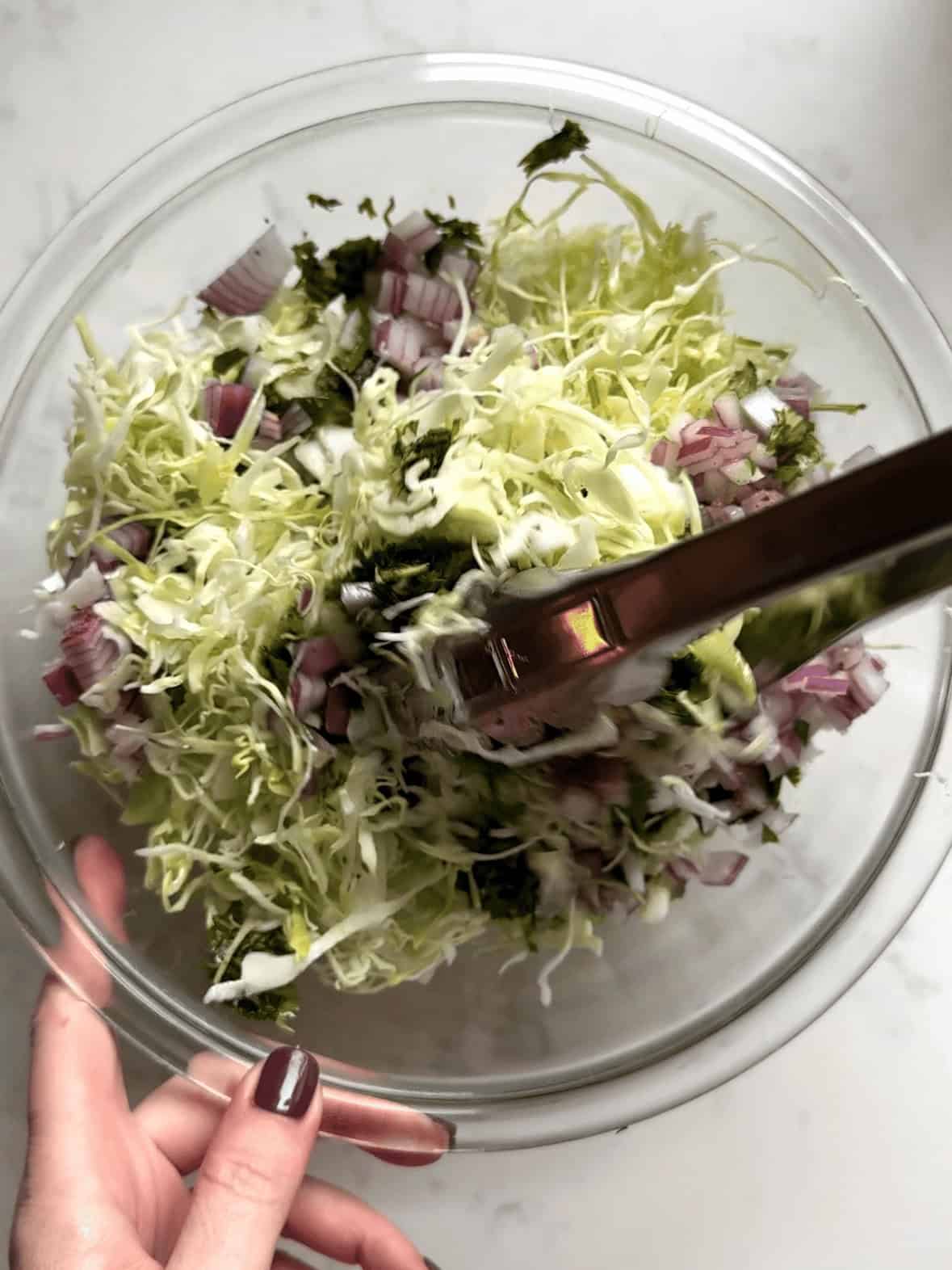 Cilantro lime cabbage slaw being mixed in a bowl